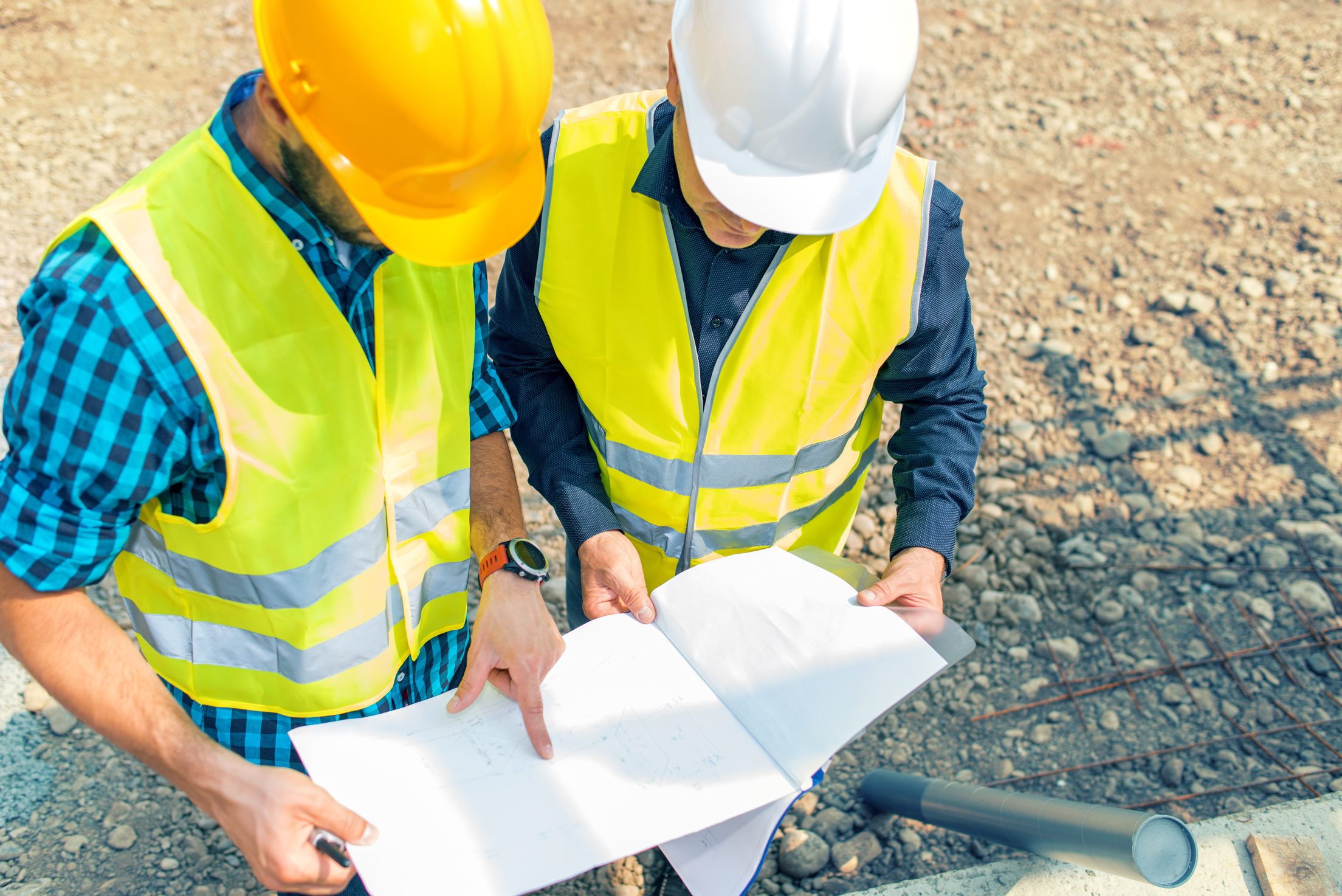 Engineer and construction site manager dealing with blueprints and projects